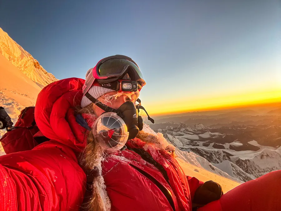 Bianca at sunrise on summit day, in her red down suit and oxygen mask