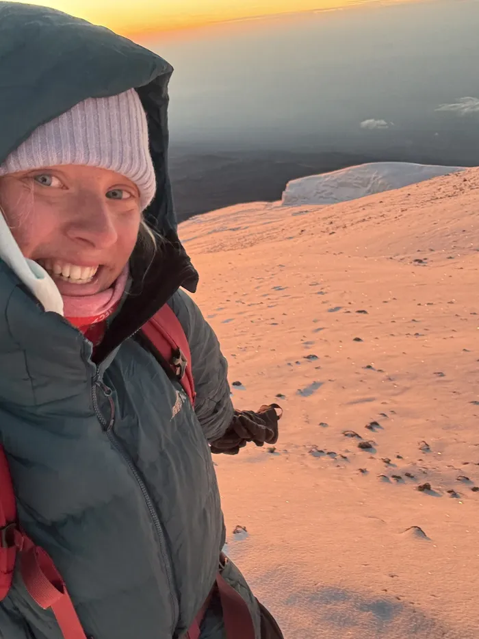 Bianca smiling at sunrise on a snowy summit slope